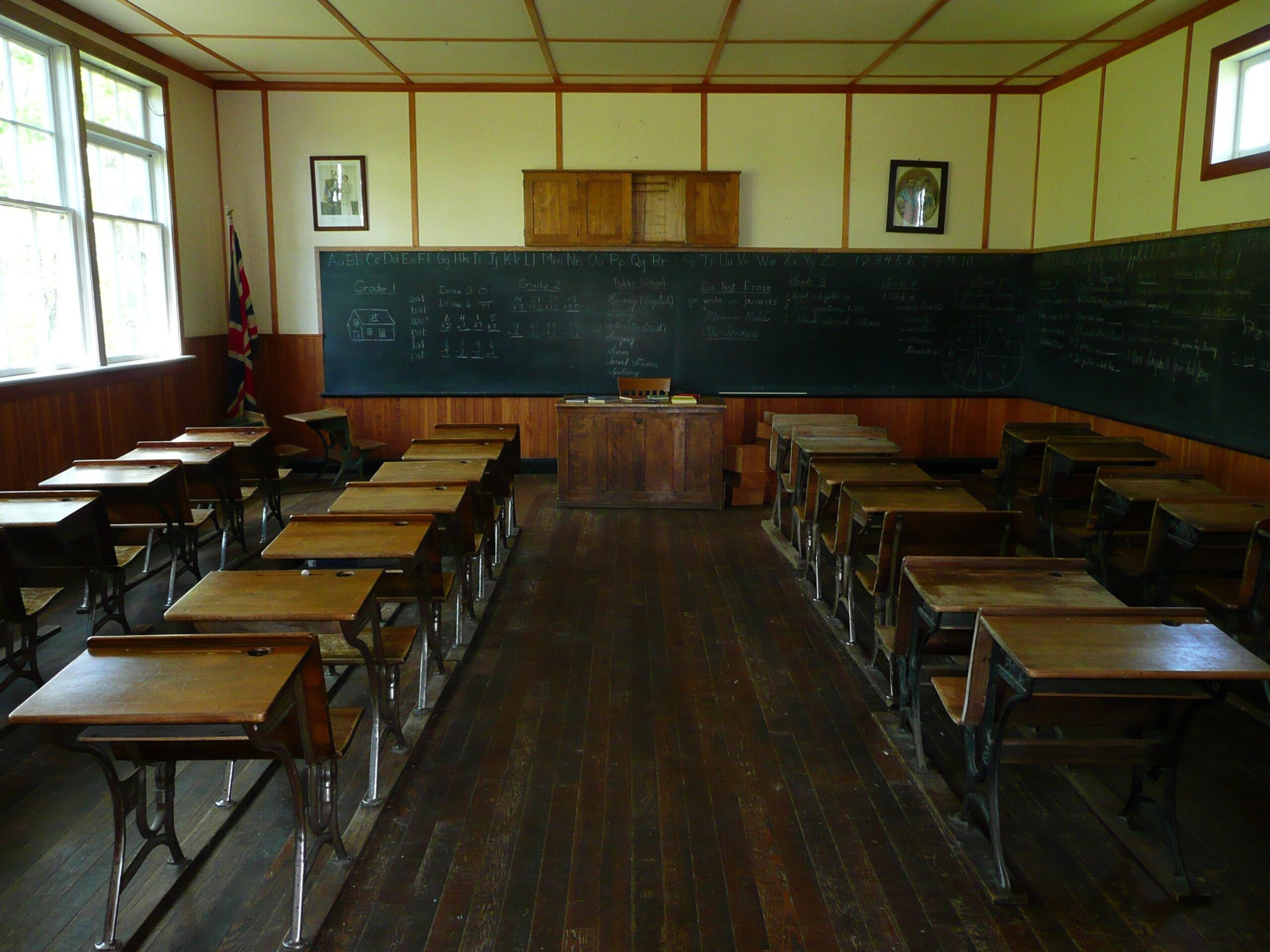 Empty classroom with vintage school chairs in rows, facing a chalkboard.